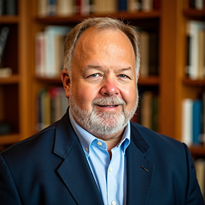 Smiling man in suit standing before bookshelf